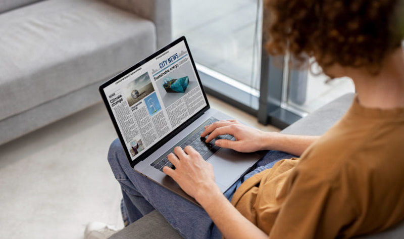 a guy is sitting on the couch with a laptop